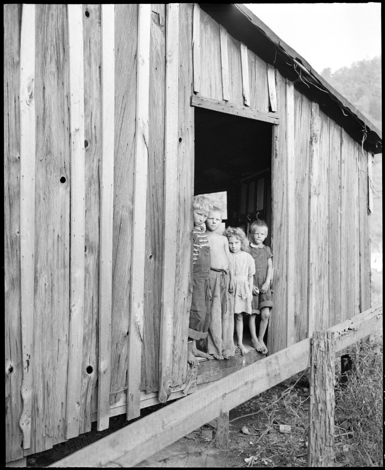 Miner's children stand in doorway of the Monroe Jones' house. Notice that this doorway has no door, a quilt is spread... - NARA - 541191