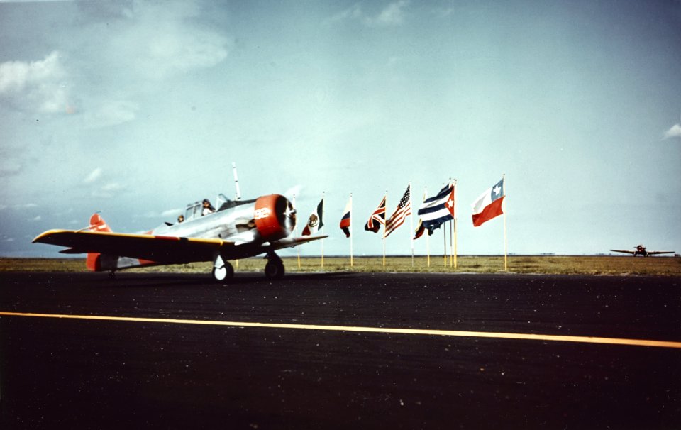 North American SNJ taxies past a display of international flags, circa in 1944 (80-G-K-13385)