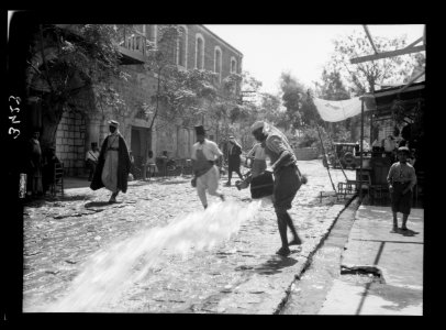 Northern views. Beisan. Main Street. Sprinkling street from open gutter LOC matpc.15327