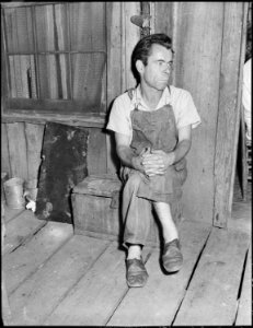 Oliver Hinkle, a miner, disabled for fifteen months with a crushed ankle, in the front porch of his house. Kentucky... - NARA - 541228