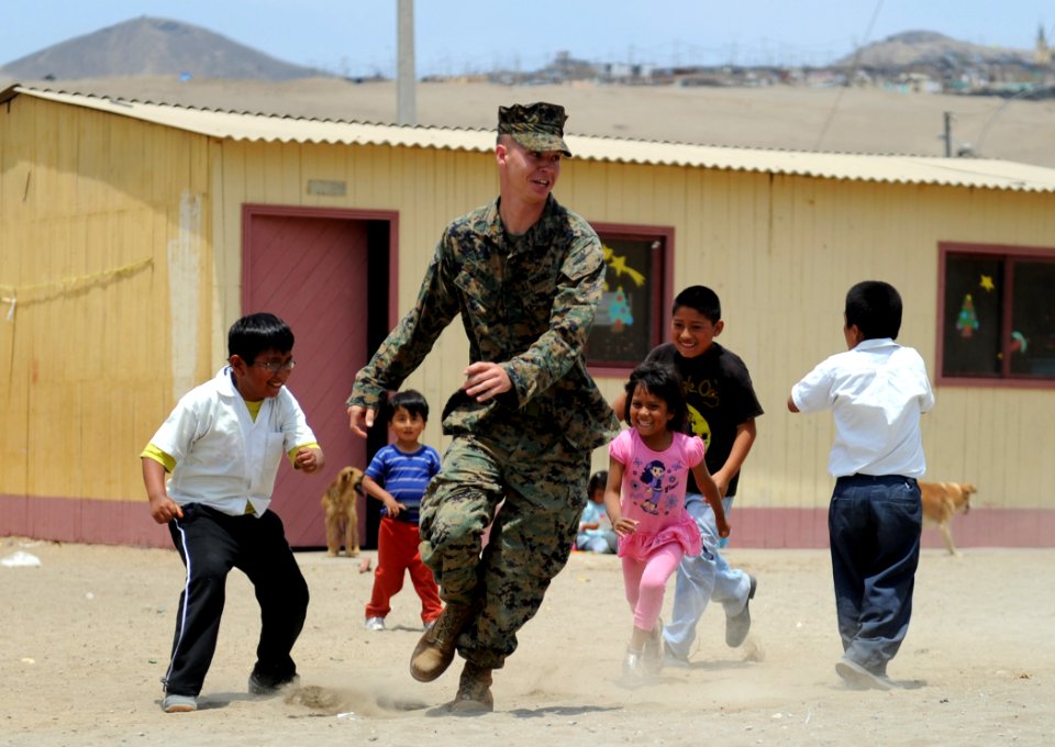 One member of 2nd Marine Logistics Group and children at Elias Aguirre Romero Elementary School in Ventanilla, Peru