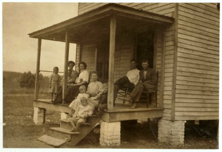 One way to keep the children out of the mill. Mrs. D.E. Hudson, South Boston, Va. Her children are seated around her. In the chairs are some of her boarders. Children are well-kept. The home LOC cph.3a29780