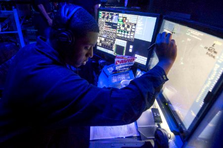 Operations Specialist 1st Class Keith Tatum stands watch in the Combat Information Center aboard the USS Normandy