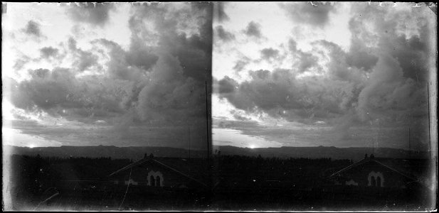 Paisatge amb una casa en primer terme i muntanyes i núvols al fons photo