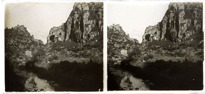 Paisatge de muntanya amb una casa al costat d'un riu