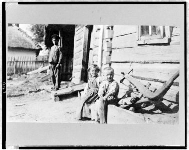 Peasant boy, girl, and man outside of log house, Russia LCCN97517363 photo