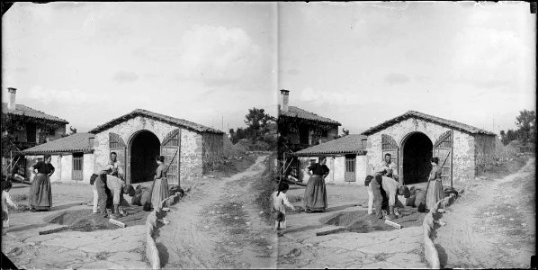 Persones a l'era d'una casa recollint el gra