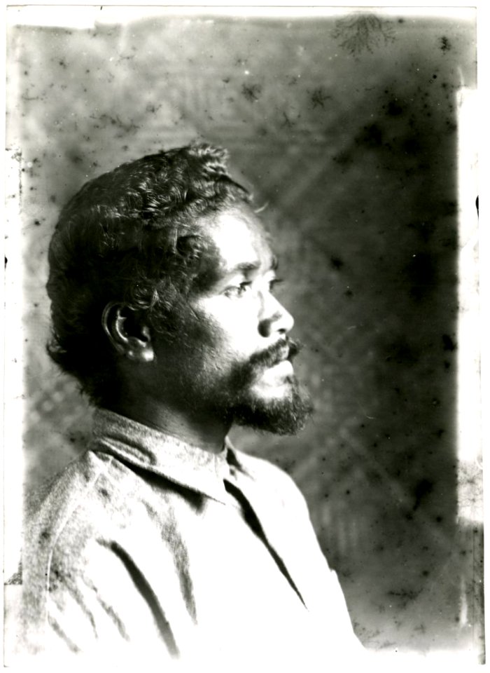 Photograph (black and white); portrait of a man in profile, in front of a plaited plant fibre wall, with a moustache and beard, wearing a shirt; Oceania. Gelatin silver print. Oc,B130.55, British Museum