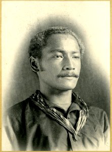 Photograph (black and white); portrait of a young chief with a moustache, wearing a shirt, with a piece of striped cloth worn around his neck; Oceania. Gelatin silver print. Oc,B48.10, British Museum