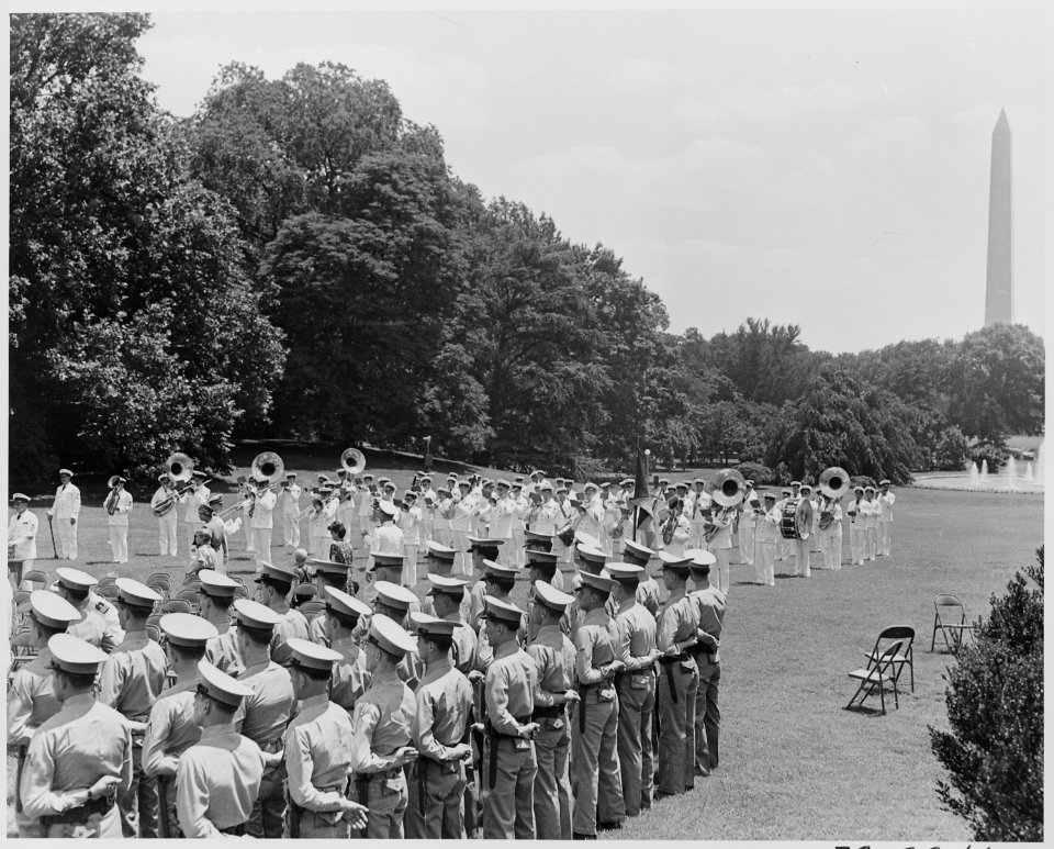 Photograph of a military band playing and troops standing at attention on the South Lawn of the White House, with the... - NARA - 199401