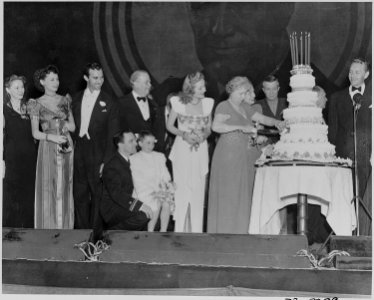 Photograph of First Lady Bess Truman cutting the cake at the Roosevelt Birthday Ball, as Margaret O'Brien, Gene... - NARA - 199254 photo