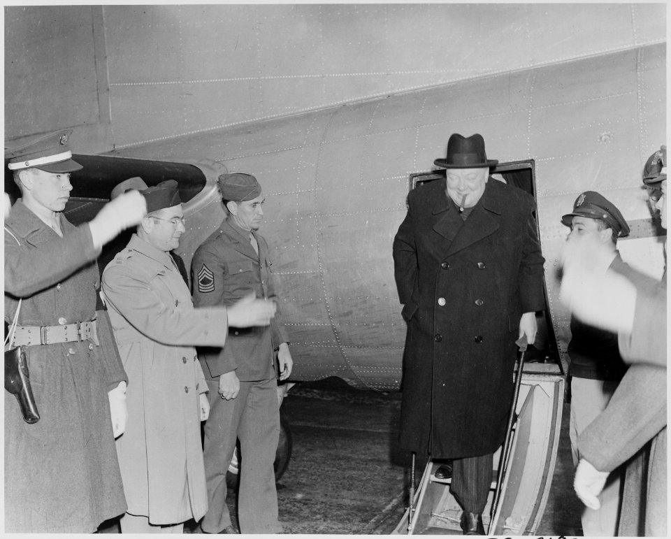 Photograph of former British Prime Minister Winston Churchill leaving his aircraft and being saluted by U.S. troops... - NARA - 199347
