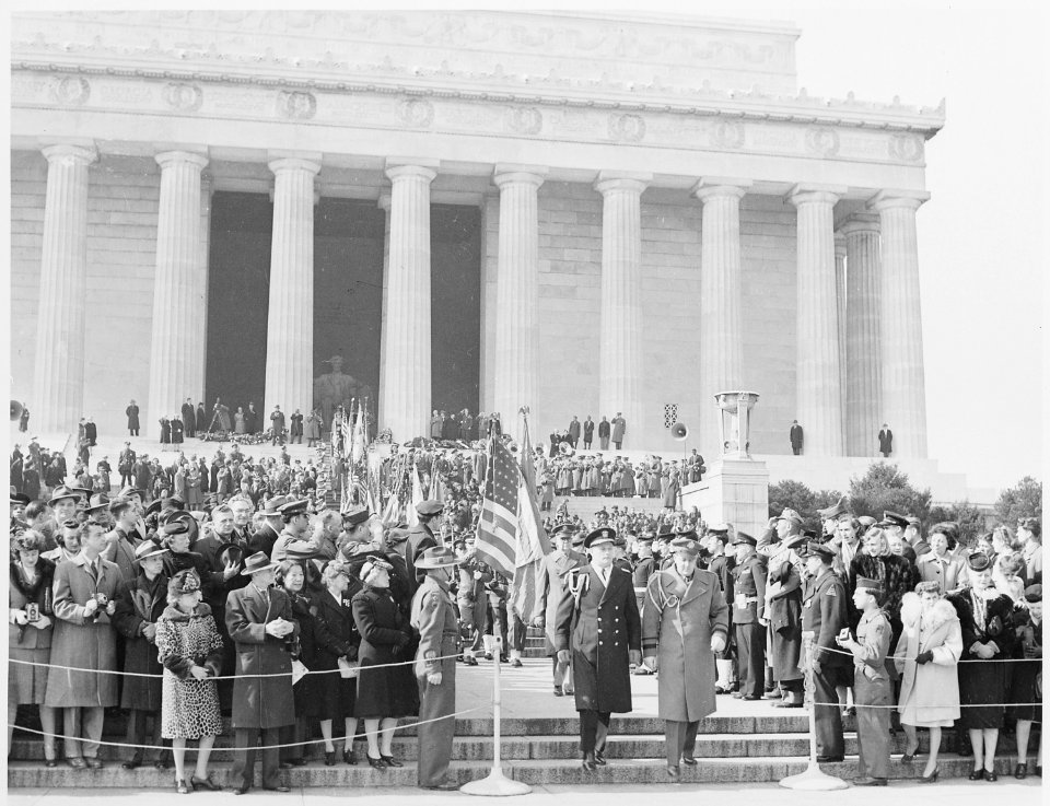 Photograph of military officers walking down the steps of the Lincoln Memorial past a color guard and a large crowd... - NARA - 199500