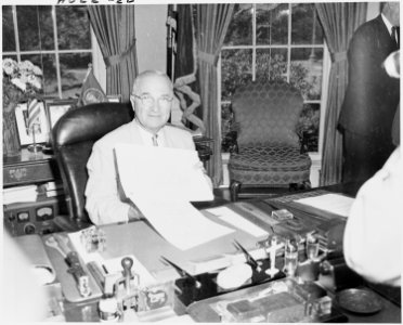 Photograph of President Truman at his desk in the Oval Office, displaying the National Security Act Amendments of... - NARA - 200169