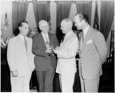 Photograph of President Truman in the Oval Office, receiving a gold pass to all games of the All-America Football... - NARA - 200170