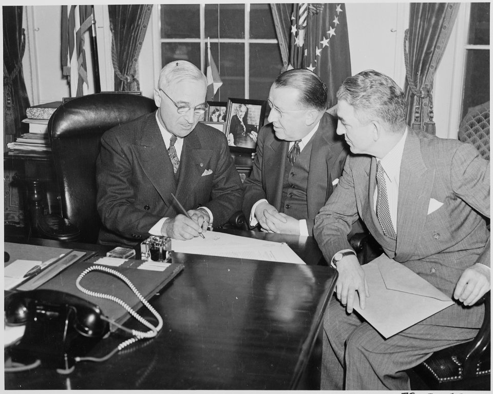 Photograph of President Truman signing S. 591, the Red Cross Reorganization Bill, at his desk in the Oval Office, as... - NARA - 199537