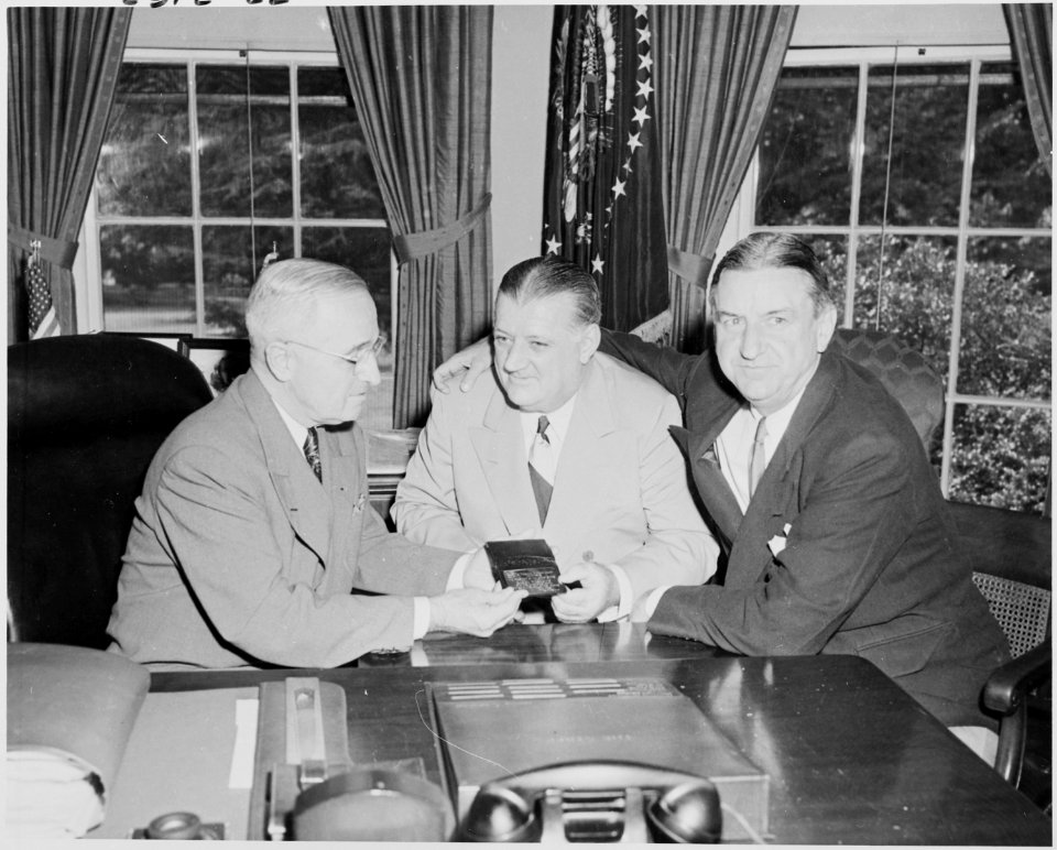 Photograph of President Truman at his desk in the Oval Office, receiving his annual pass to National Football League... - NARA - 200160