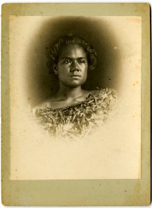 Photograph (black and white); cabinet card; portrait of a woman posing in front of a neutral backdrop; she wears an off-the shoulder dress made of woven plant material; Tonga. Albumen print. Oc,B47.16, British Museum