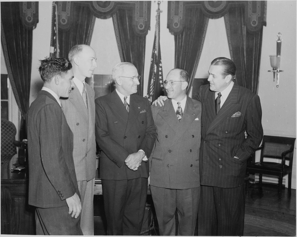 Photograph of President Truman greeting crew members from an around-the-world flight in the Oval Office. - NARA - 199591