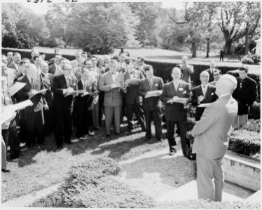 Photograph of President Truman posing outside the White House for a group of visiting cartoonists, as they sketch his... - NARA - 200159