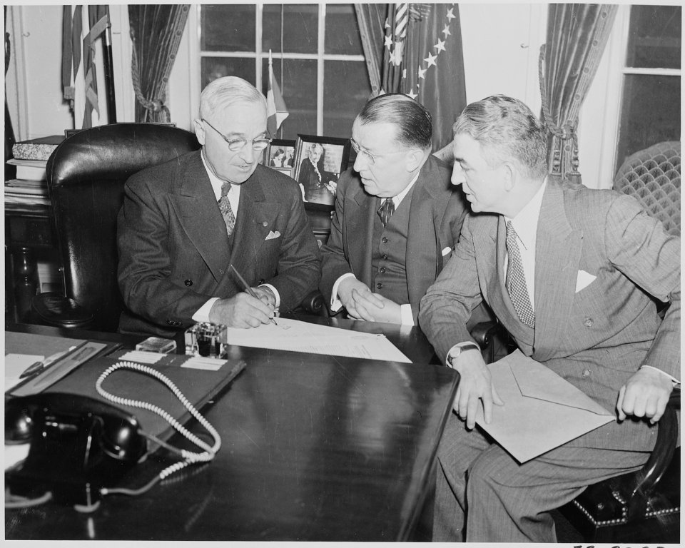 Photograph of President Truman signing S. 591, the Red Cross Reorganization Bill, at his desk in the Oval Office, as... - NARA - 199538