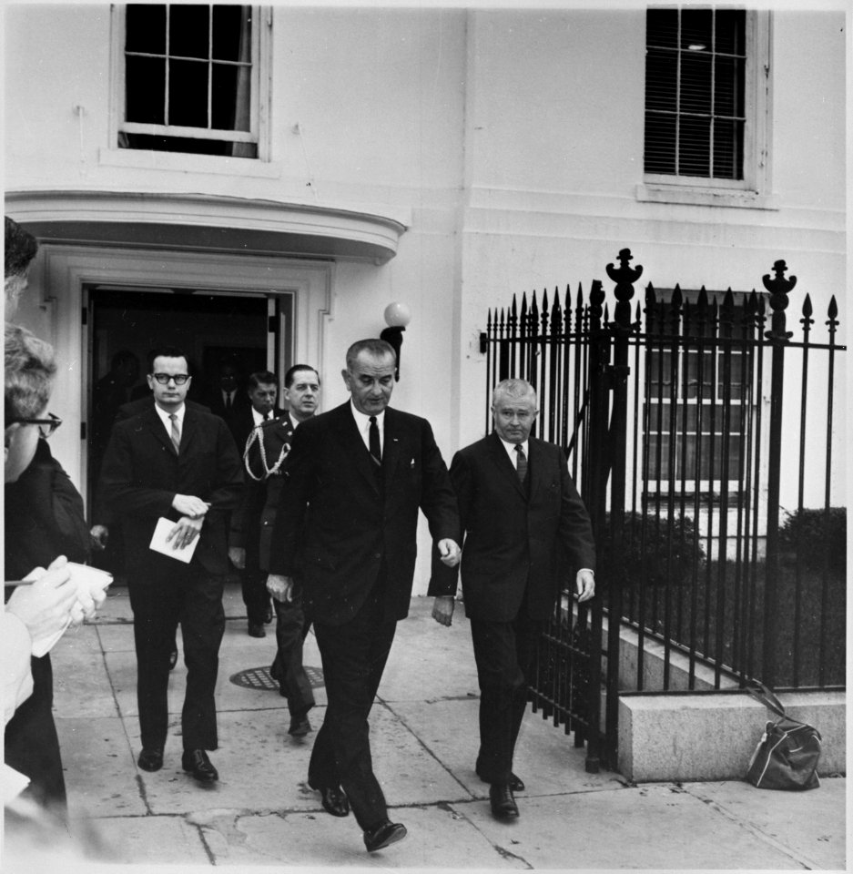 Photograph of President Lyndon B. Johnson leaving the White House, accompanied by aides, during the weekend of... - NARA - 200447