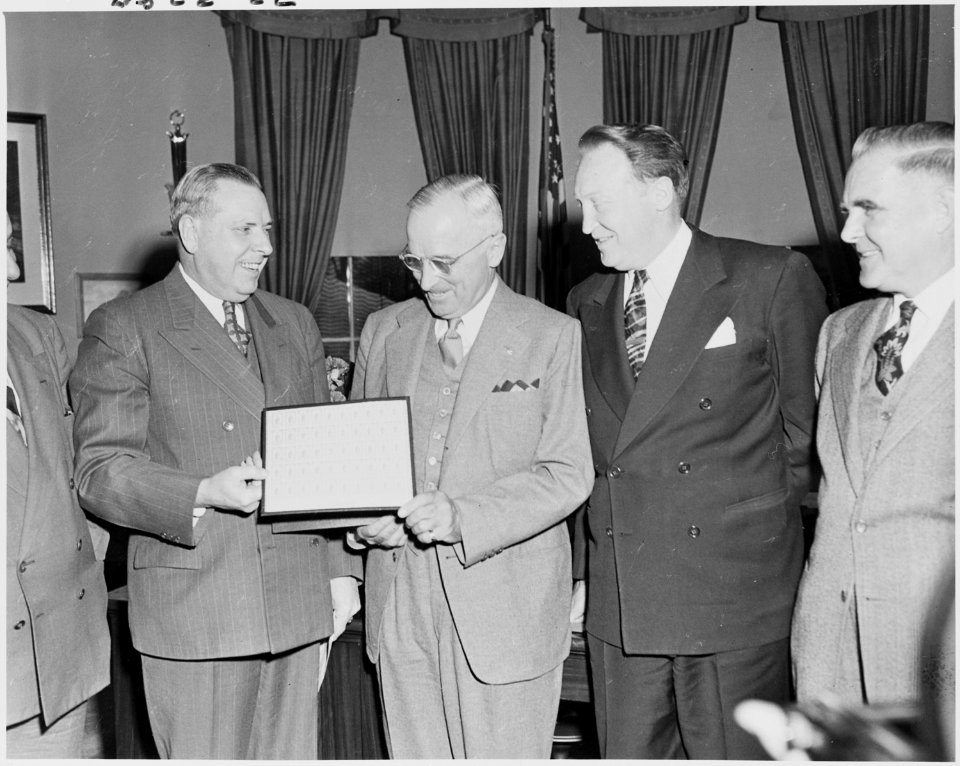 Photograph of President Truman in the Oval Office receiving a sheet of the new Freedom Stamps, issued in honor of the... - NARA - 200200