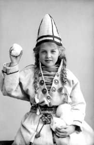 Pike i sameliknende drakt med kofte, lue og belte. I hendene holder hun jukse snøballer - Norsk folkemuseum - NF.25780-852