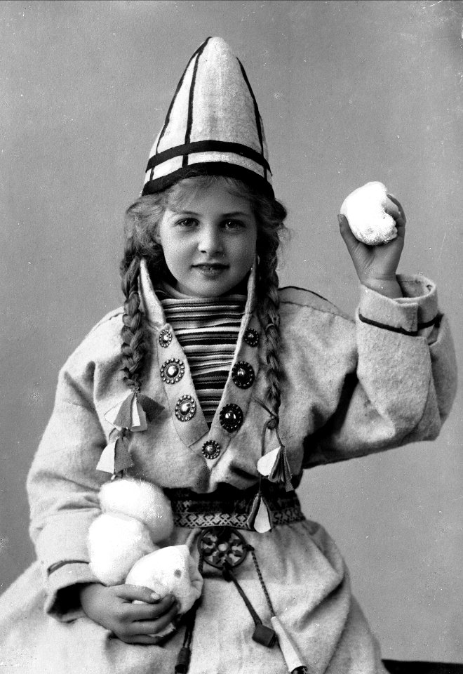 Pike i sameliknende drakt med kofte, lue og belte. I hendene holder hun jukse snøballer - Norsk folkemuseum - NF.25780-856