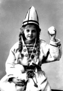 Pike i sameliknende drakt med kofte, lue og belte. I hendene holder hun jukse snøballer - Norsk folkemuseum - NF.25780-854