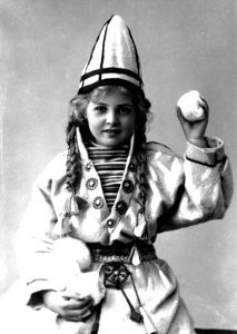 Pike i sameliknende drakt med kofte, lue og belte. I hendene holder hun jukse snøballer - Norsk folkemuseum - NF.25780-858