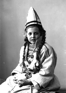 Pike i sameliknende drakt med kofte, lue og belte. I hendene holder hun jukse snøballer - Norsk folkemuseum - NF.25780-855