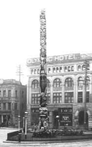 Pioneer Square totem pole with the Olympic Block in the background, Seattle, ca 1911 (WARNER 629) (cropped)