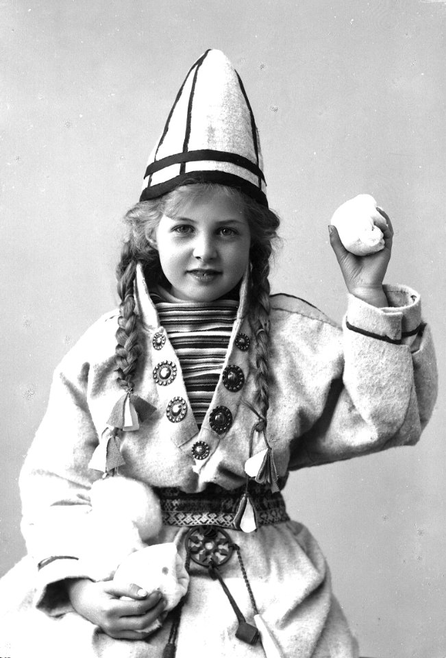 Pike i sameliknende drakt med kofte, lue og belte. I hendene holder hun jukse snøballer - Norsk folkemuseum - NF.25780-853