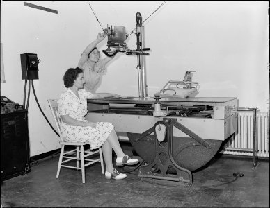 R.N., Hazel Jamison, adjusts the X-Ray machine in company dispensary for X-Ray photograph of patient's arm. Koppers... - NARA - 540951