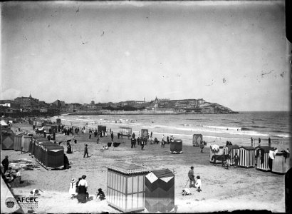 Platja de Sant Sebastià amb gent i casetes i voltada d'edificis