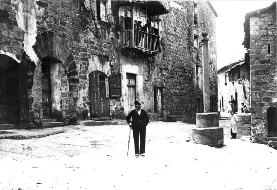 Plaça de Casserres i un home, al fons dos homes en un balcó