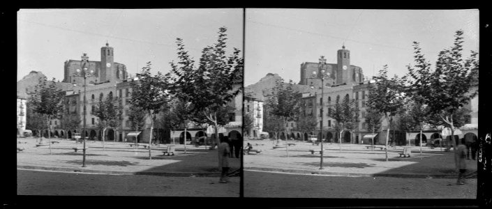 Plaça Mercadal de Balaguer amb arbres, pòrtics i l'església que sobresurt darrera les cases (AFCEC DEGOLLADA X 115)