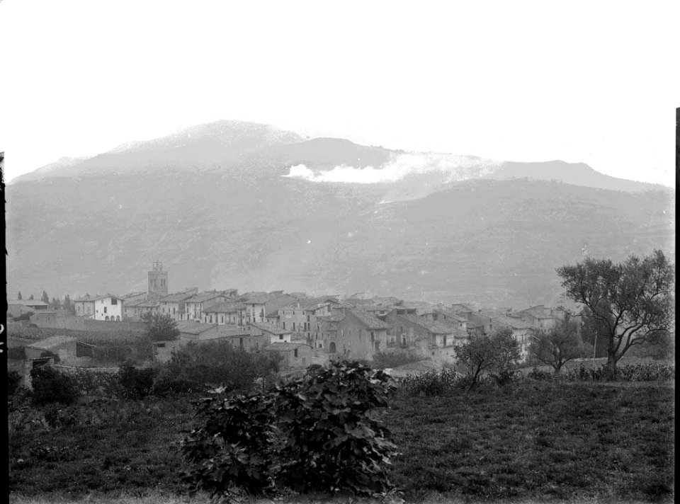 Poble d'Organyà vist des del camí de Montamisell amb muntanyes i boira al fons