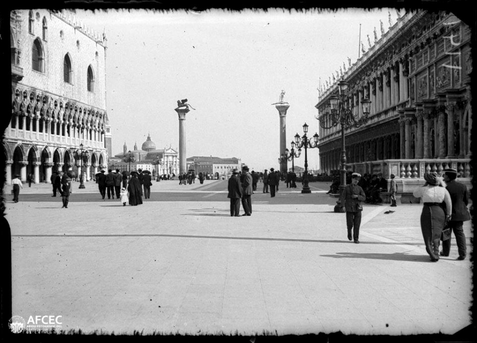 Plaça de Sant Marc amb gent passejant i al fons dues columnes amb escultures