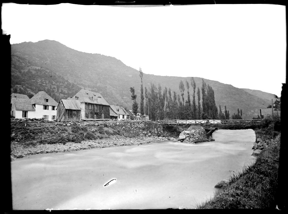 Pont de Lés sobre el riu Garona amb el poble i muntanyes al fons