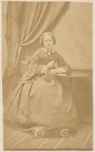 Portret van een onbekende jonge vrouw zittend op stoel naast tafeltje foto 2 (max res)