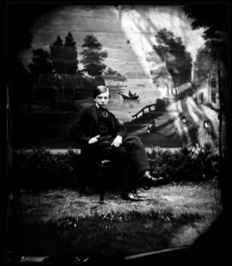 Portret van een onbekende jongeman, zittend op stoel in de tuin van werf De Reus, Grote Bickersstraat 4 foto 2 (max res) photo