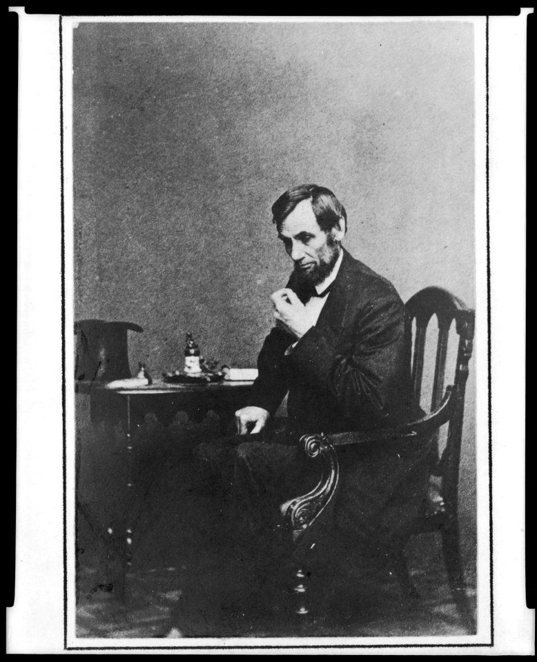 President Abraham Lincoln, seated next to small table, in a reflective pose, May 16, 1861, with his hat visible on the table LCCN2009630686