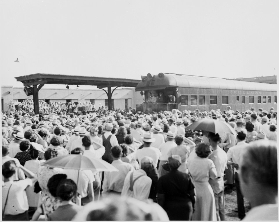 President Harry S. Truman on the rear platform of the presidential train, in a station, in the distance, with a crowd... - NARA - 199928