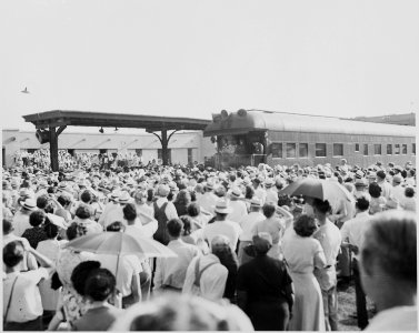 President Harry S. Truman on the rear platform of the presidential train, in a station, in the distance, with a crowd... - NARA - 199928