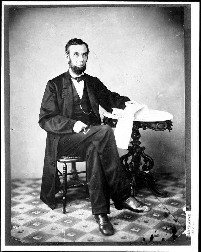 Presidenet Abraham Lincoln, seated next to a table LCCN2013645575