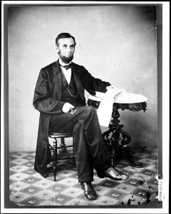 Presidenet Abraham Lincoln, seated next to a table LCCN2013645575