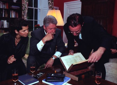 President Bill Clinton and musician Bono look at a book