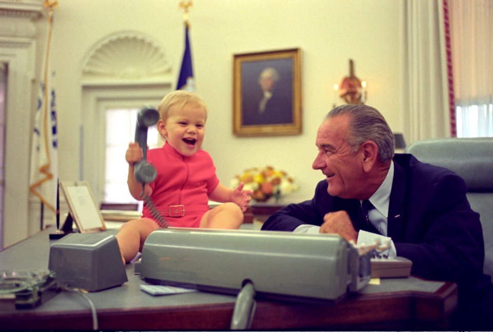 President Lyndon B. Johnson watches his grandson play with the telephone